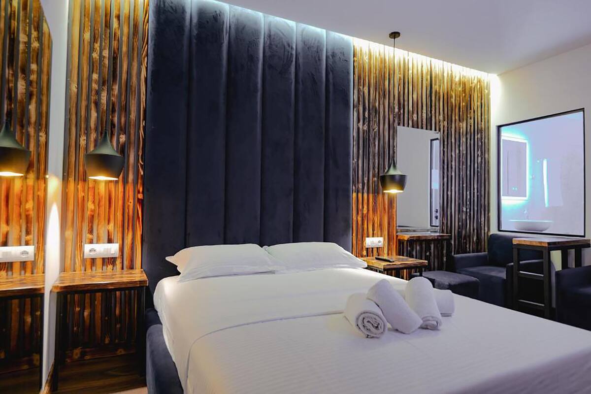 Una habitación de hotel moderna con una cama grande, un televisor y paneles de madera en las paredes.