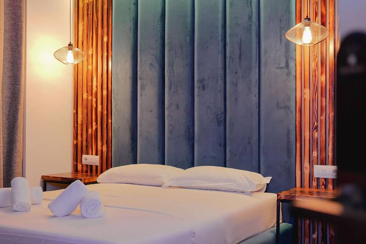 Una habitación de hotel con una cama grande, dos mesitas de noche y un panel de pared de madera.