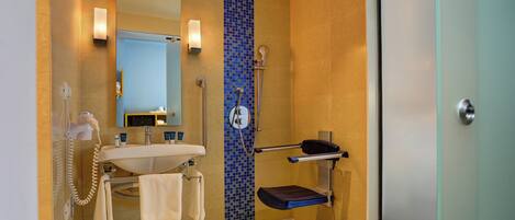 Un baño moderno con lavamanos, espejo, toallero y cabina de ducha con puerta de cristal.