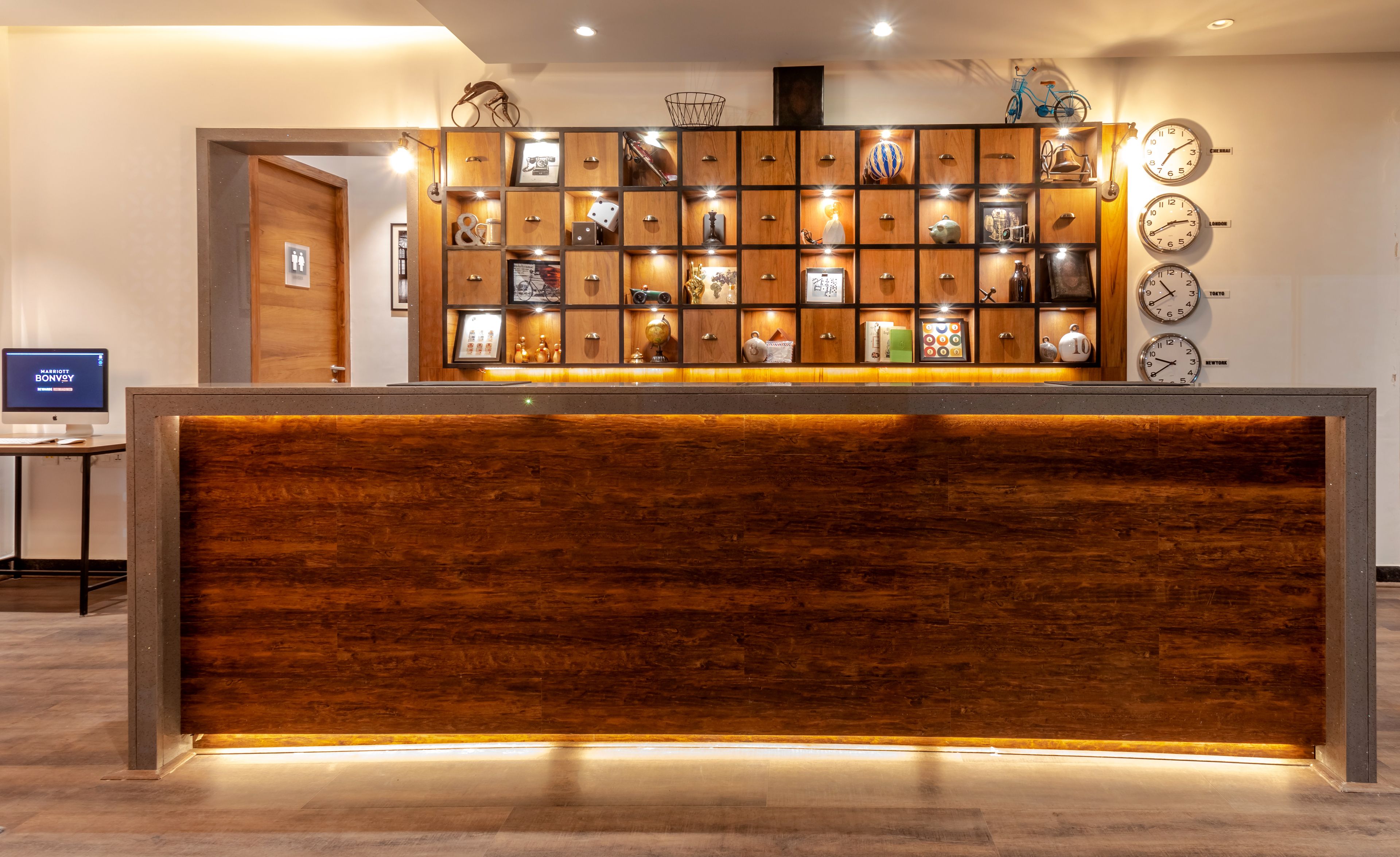 A reception desk with a wooden panel and a wall display of clocks and framed photos.