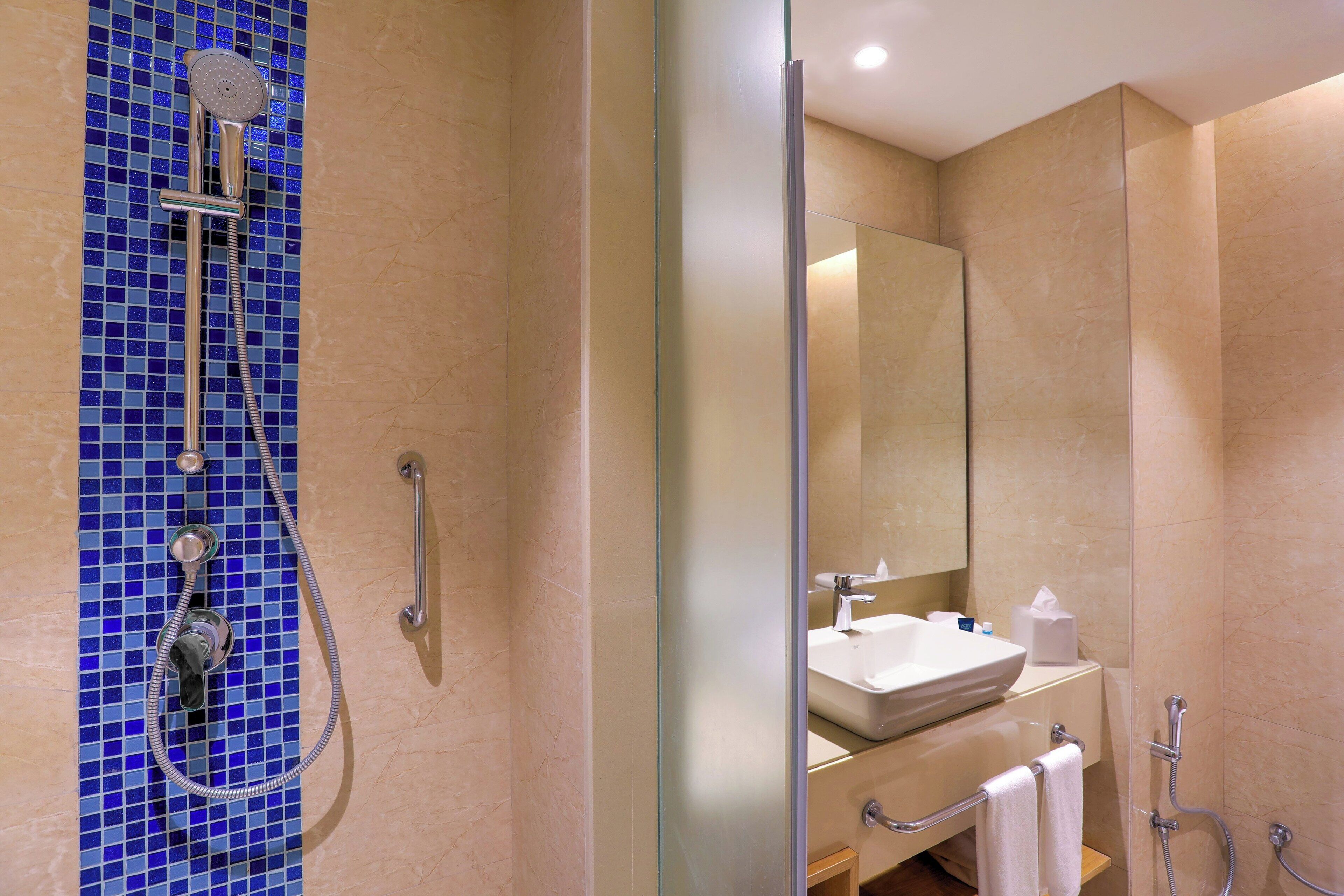 A modern bathroom with a glass shower enclosure, a sink, and a mirror.