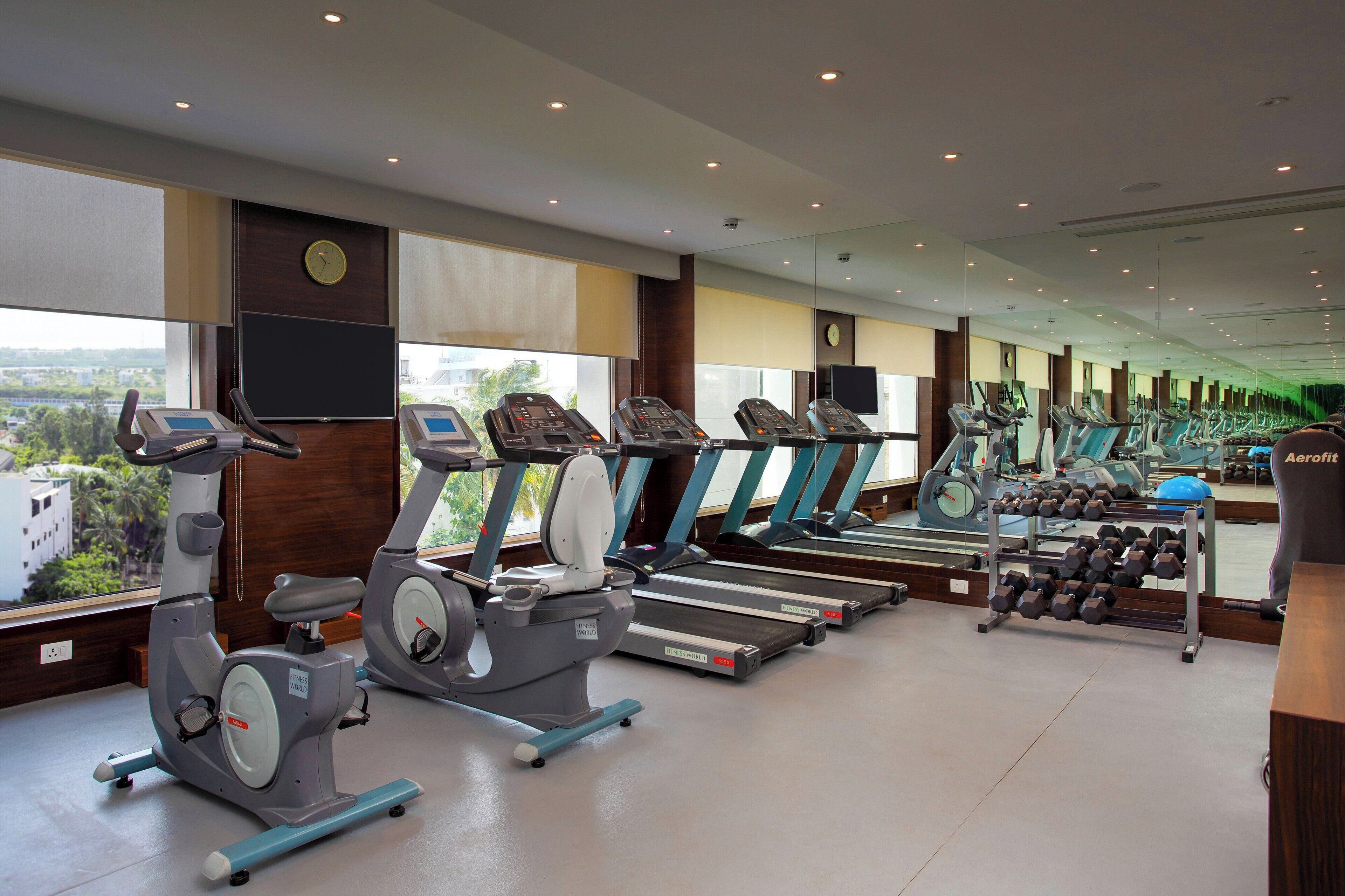 Un gimnasio equipado con bicicletas estáticas, cintas de correr y mancuernas.