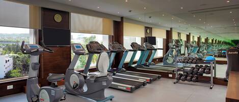 Un gimnasio equipado con bicicletas estáticas, cintas de correr y mancuernas.