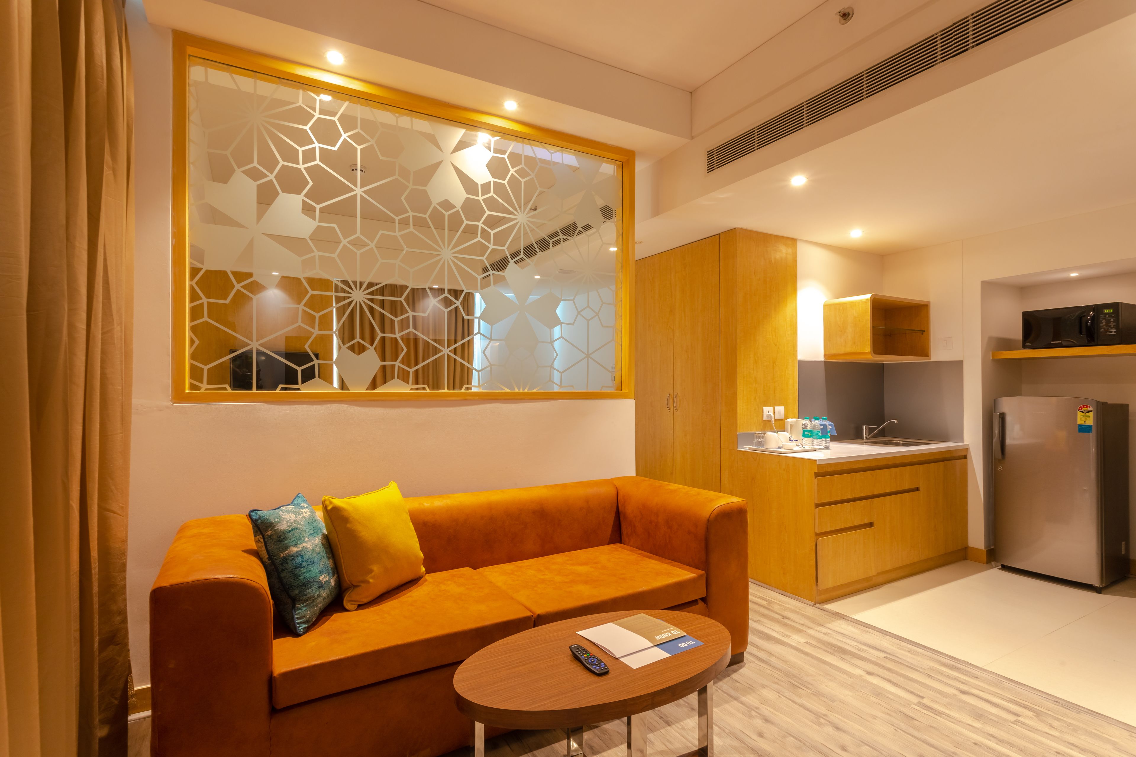 A modern living area with a sofa, a coffee table, and a kitchen with a refrigerator and microwave.