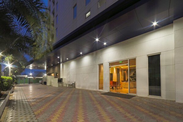 Una entrada de hotel con un camino de baldosas que lleva a la recepción.