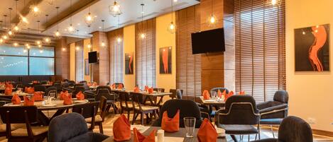A restaurant with multiple tables, chairs, and hanging lights.