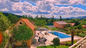 A villa with a swimming pool, outdoor seating, and a view of the surrounding landscape. - Holiday House Iva (Imotski)
