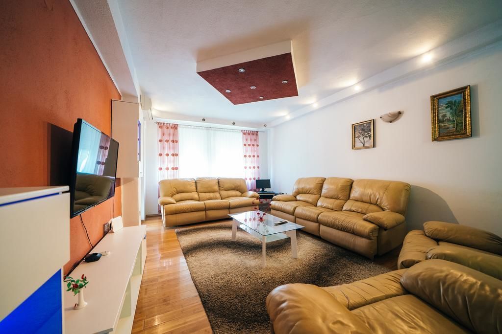 A living room with two sofas, a coffee table, a TV, and a desk with a computer.