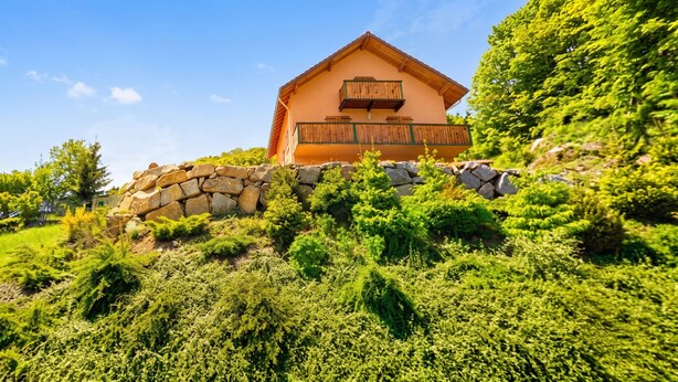A house with a stone wall and wooden balcony, surrounded by lush greenery. - Homerez - Apartment in Cornimont (Cornimont)