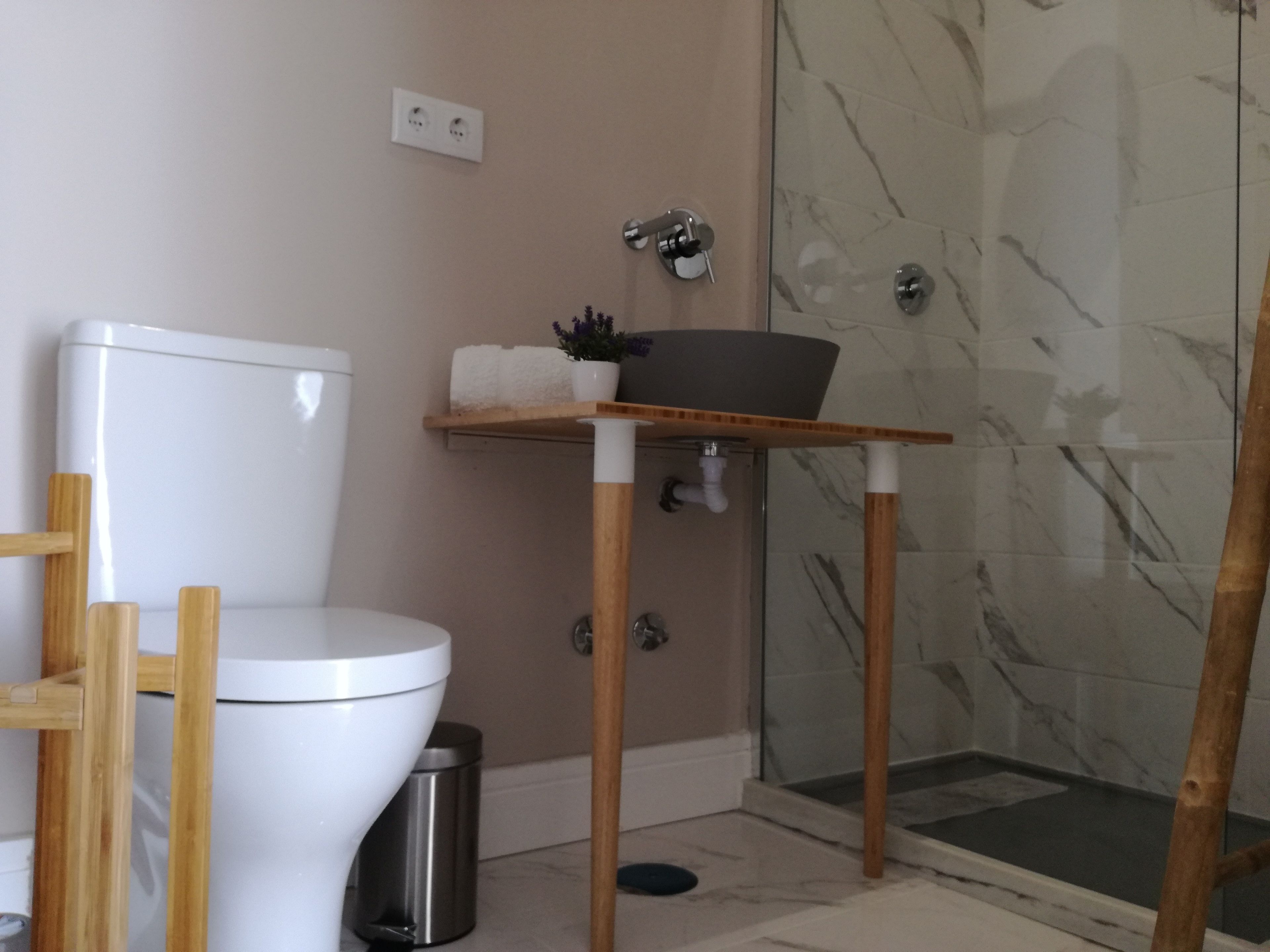 Une salle de bain équipée de toilettes, d’une douche et d’un lavabo, avec une étagère en bois.