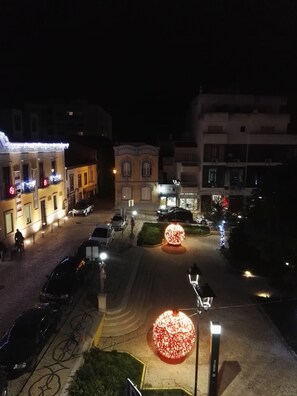 Une vue nocturne d’une rue, avec des bâtiments illuminés, une installation lumineuse sphérique et une piste cyclable.