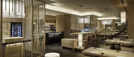 A modern restaurant with a clean, minimalist design, featuring a mix of dining and bar areas, and a contemporary interior with neutral tones and ample lighting.