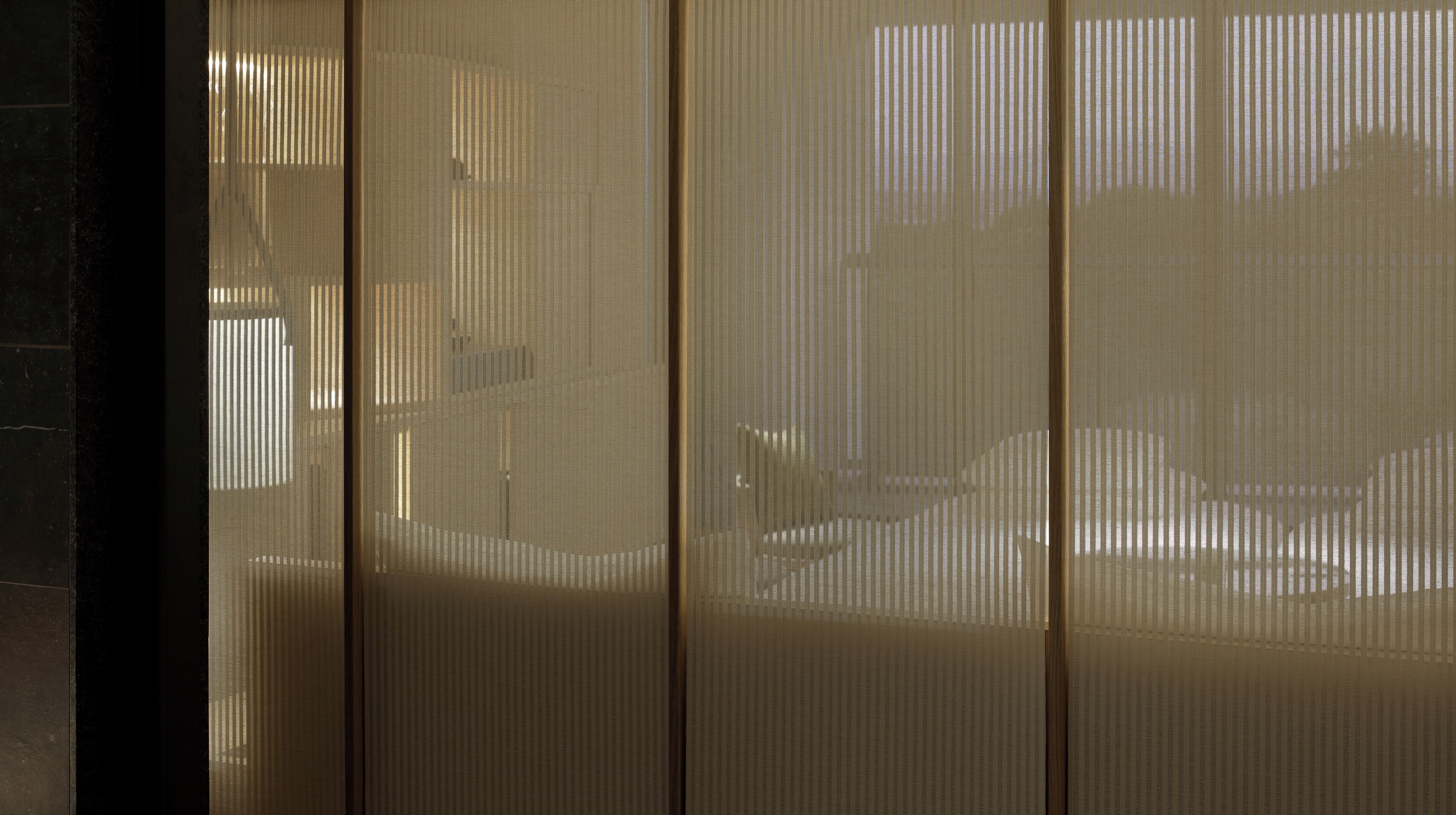 A room with a large window covered by a sheer curtain, allowing natural light to enter.