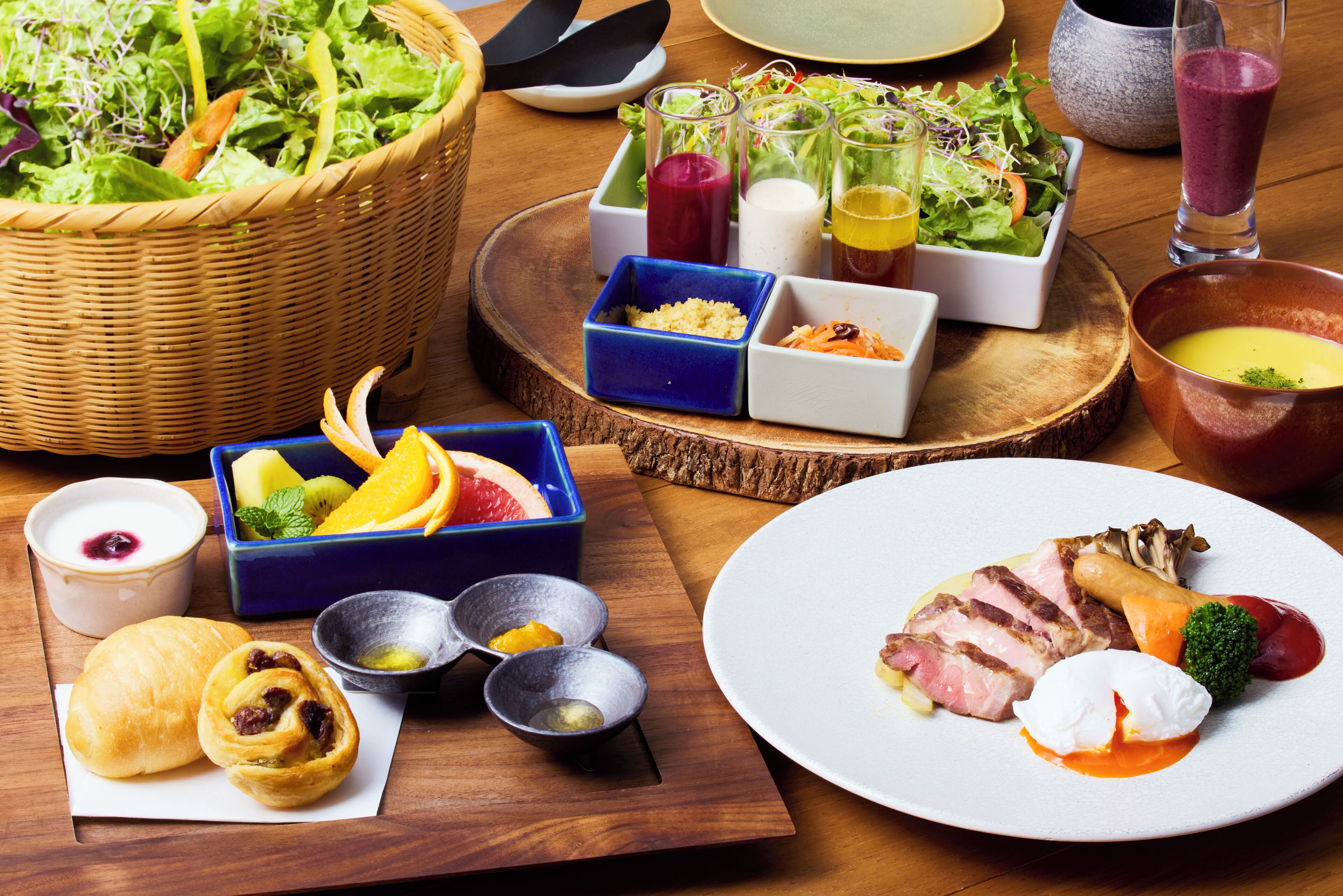 Variedad de alimentos como ensalada, fruta, sopa y platos de carne, dispuestos sobre una mesa de madera.