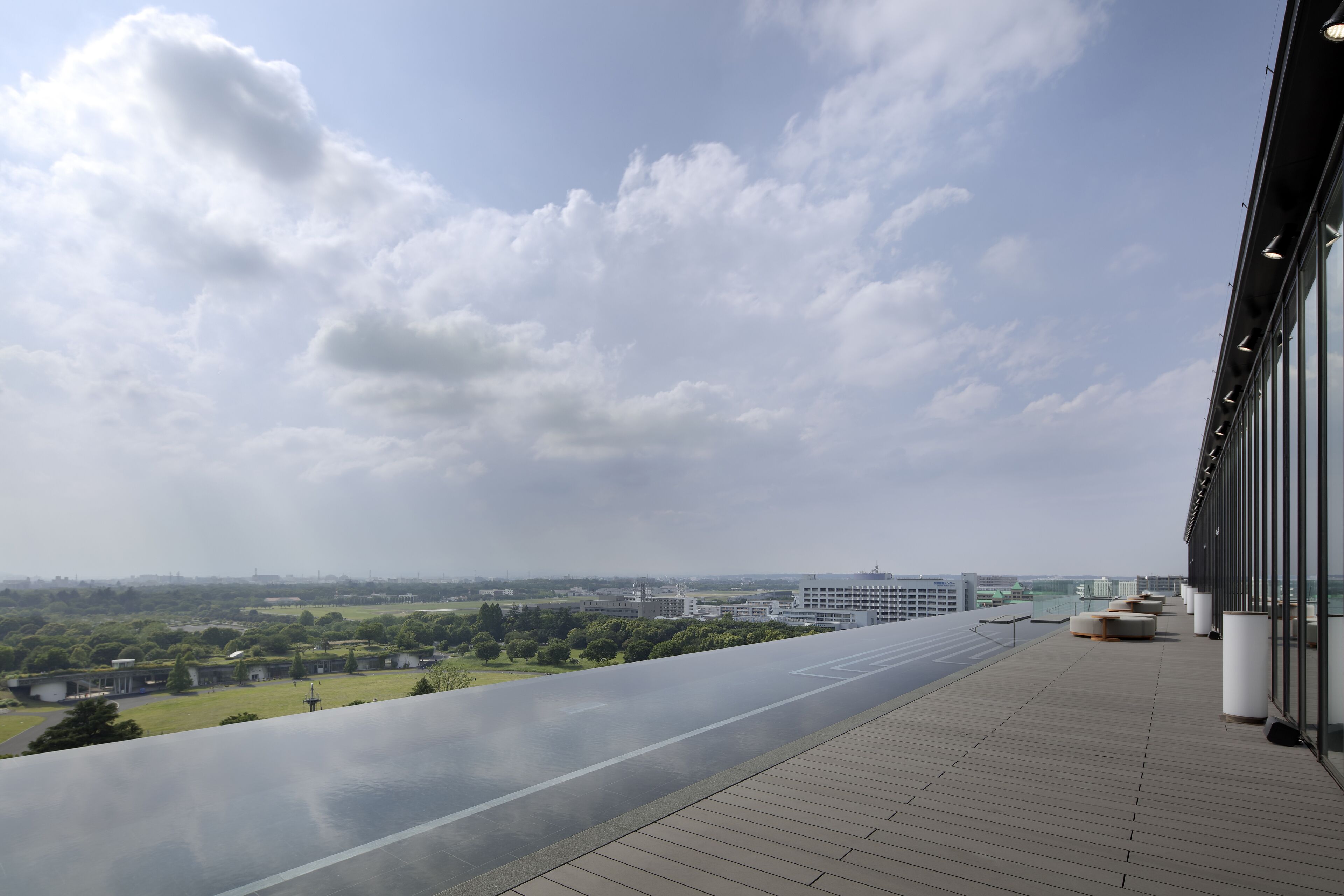 A rooftop terrace with a view of a cityscape and greenery.