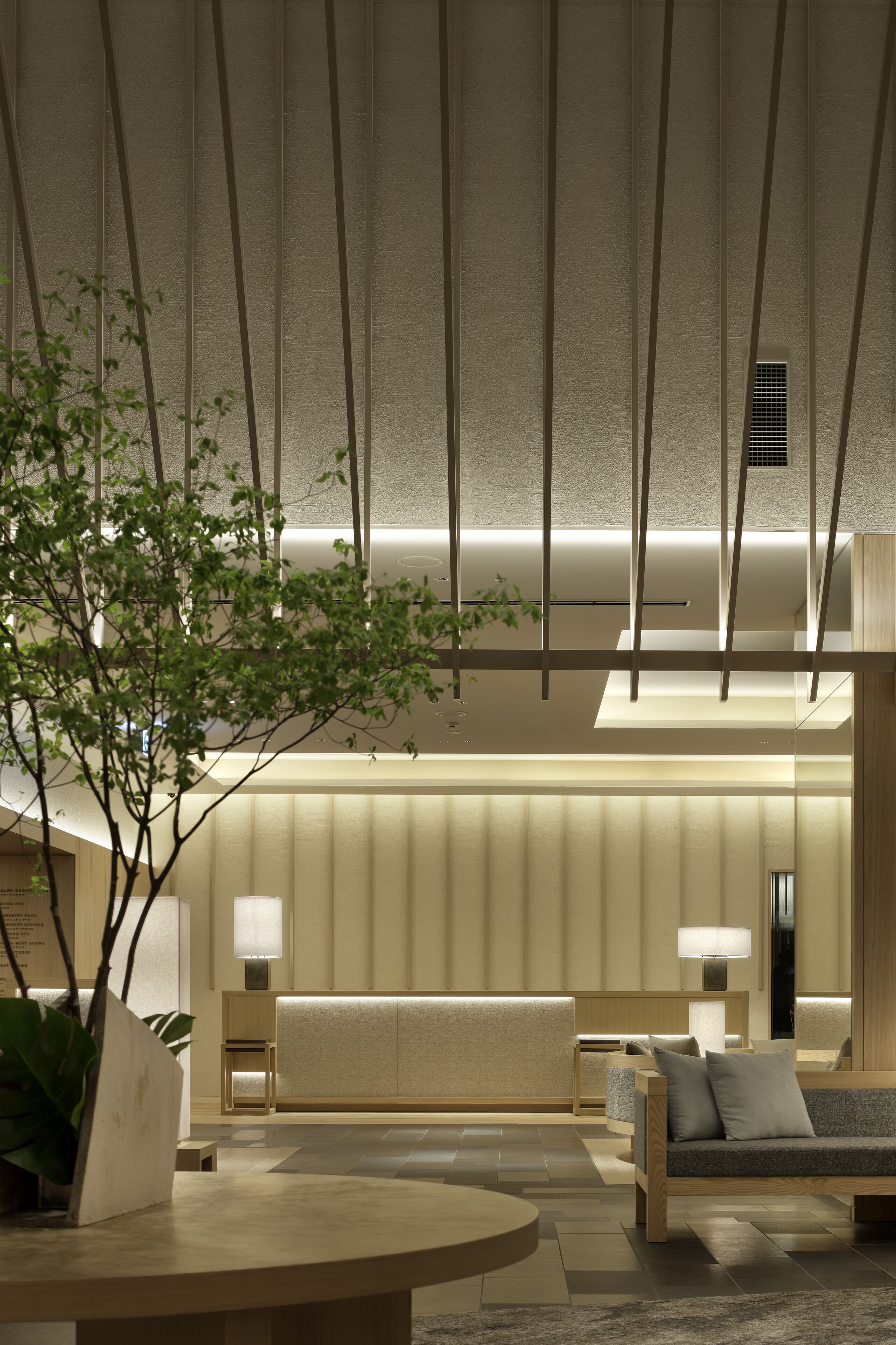 Un moderno vestíbulo de hotel con mostrador de recepción, zona de estar y una planta grande.
