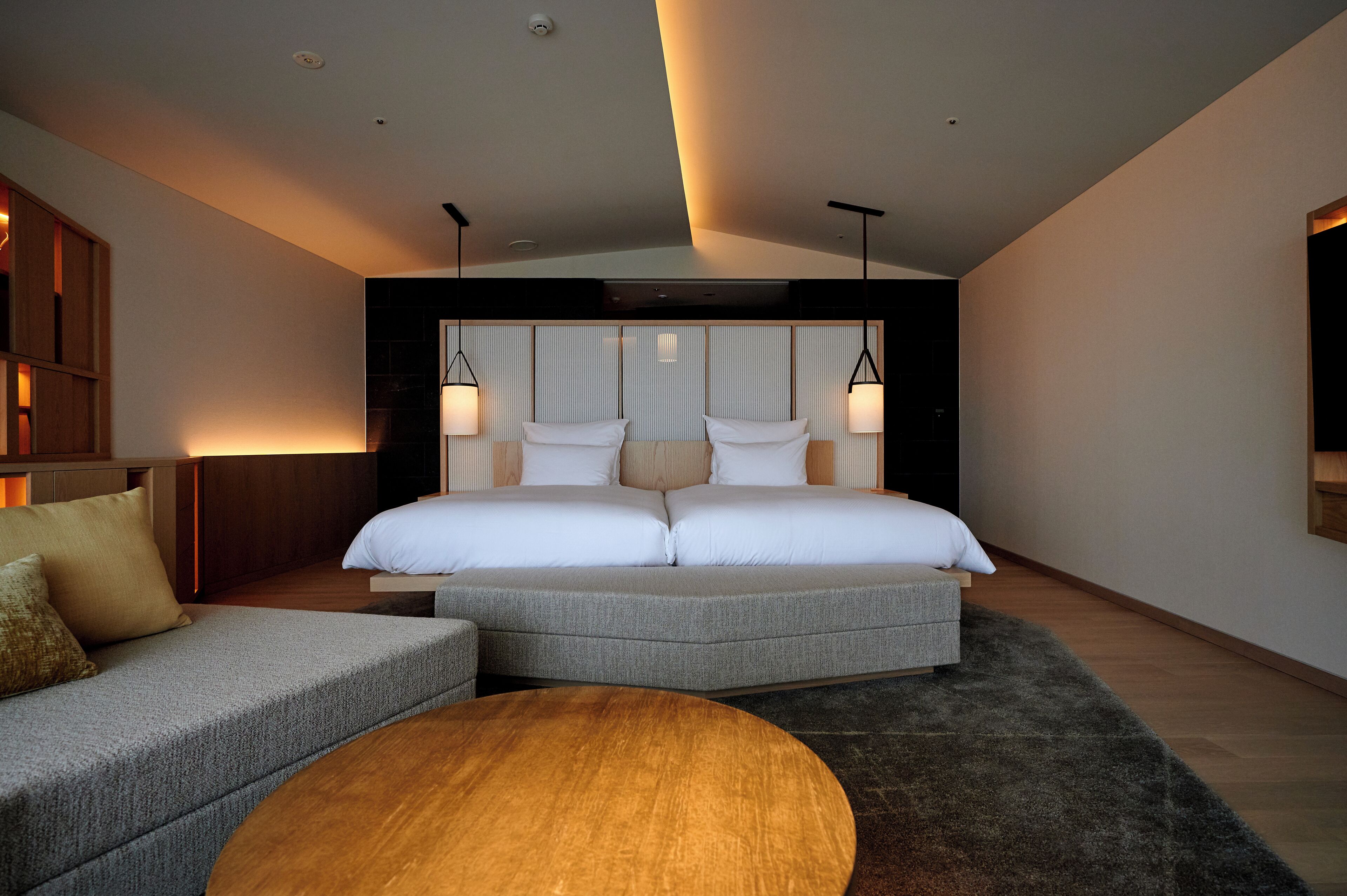A modern bedroom with a large bed, a sofa, and a round coffee table.