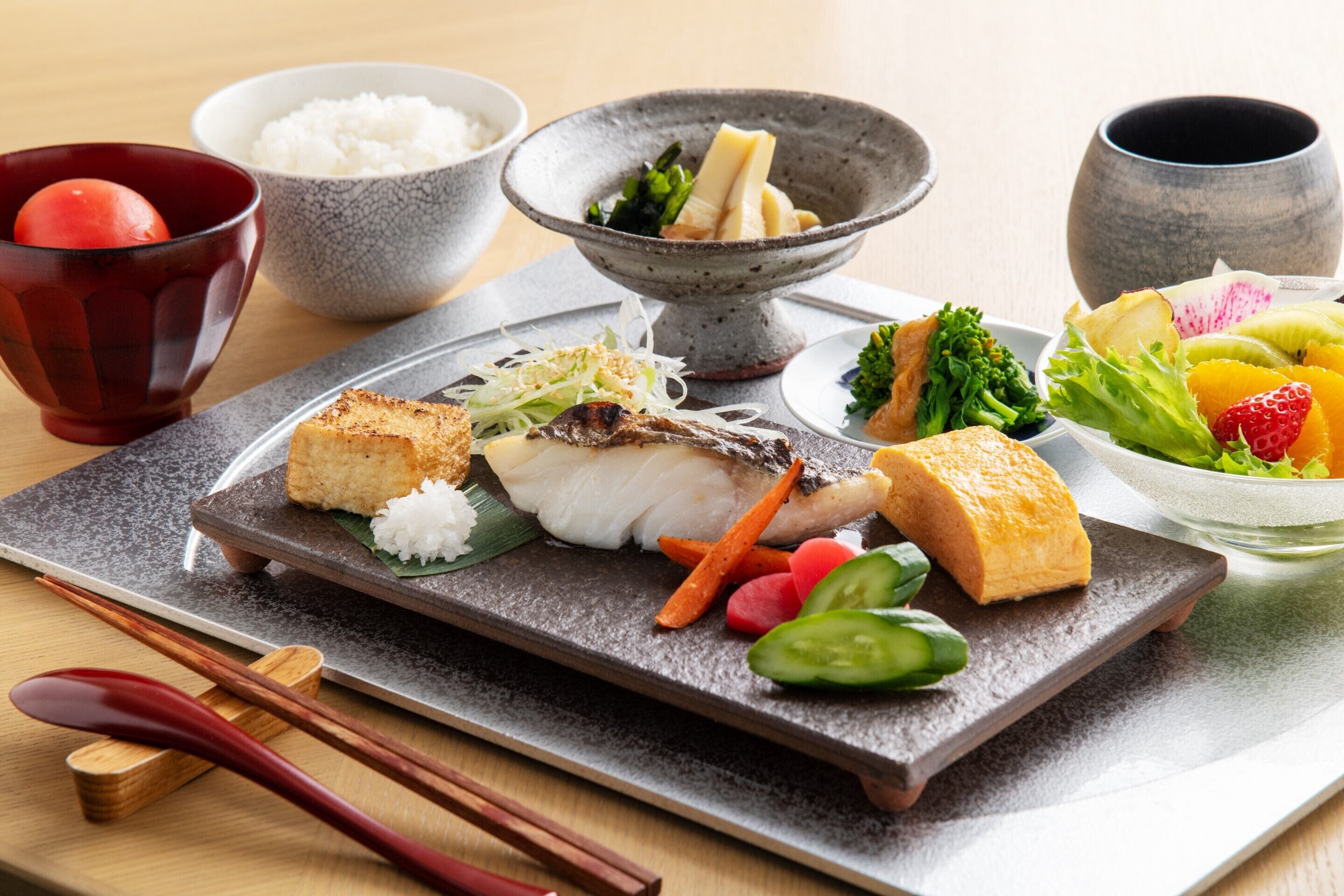 A traditional Japanese meal with rice, fish, and vegetables on a ceramic plate.