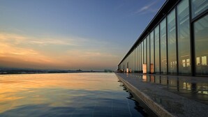 A modern building with a glass facade and a reflective pool in front. - SORANO Hotel (Tachikawa)