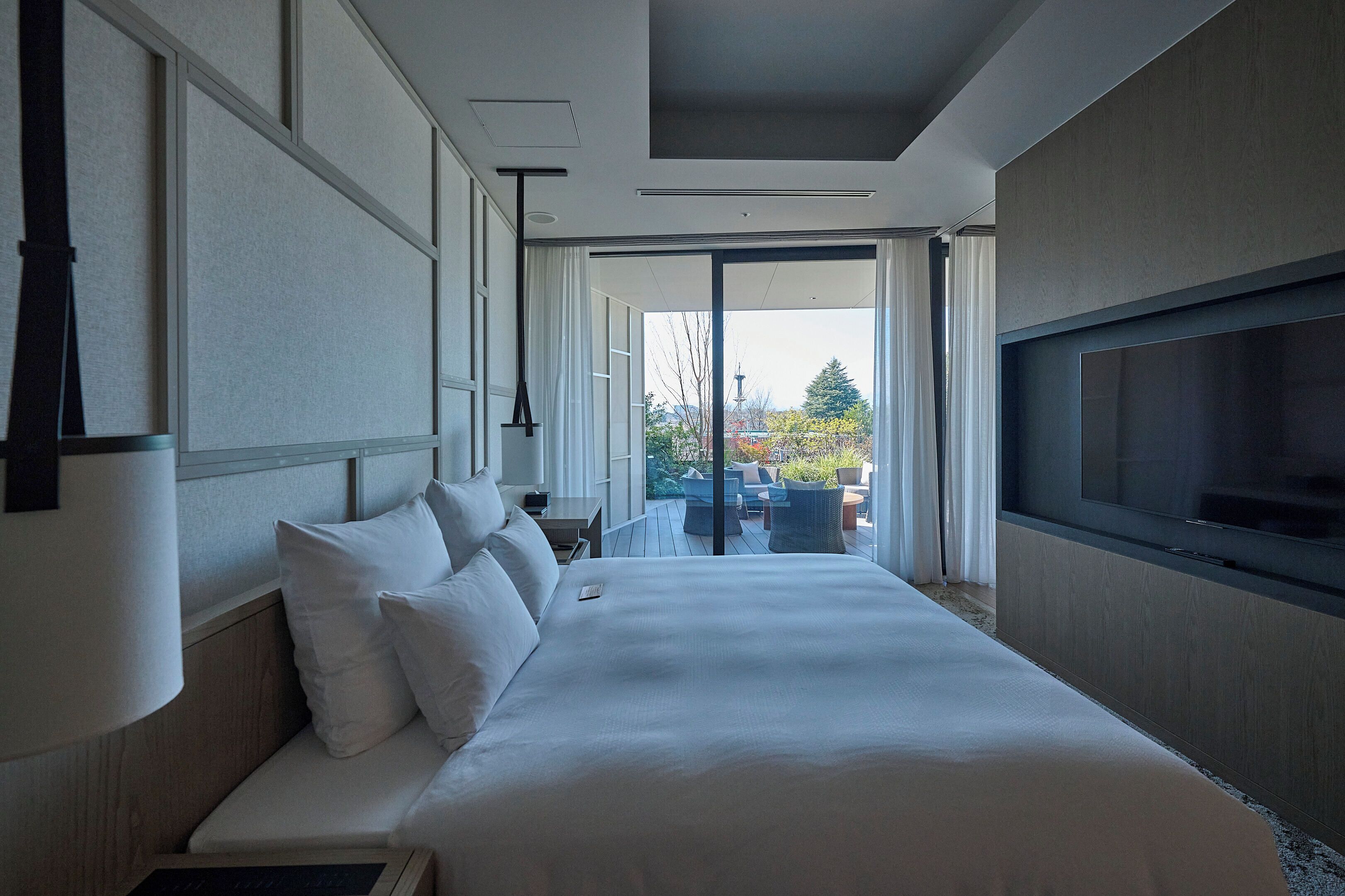 Una habitación de hotel moderna con una cama grande, televisión y vistas al exterior.