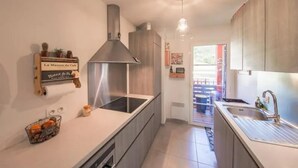 A modern kitchen with a stainless steel range hood, a built-in oven, and a sink. There is a small plant on the counter and a basket of oranges. - Soothing 4-person apartment in the heart of Erbalunga (Erbalunga)