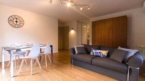 A modern living room with a dining area, a wooden cabinet, and a wall clock. - Soothing 4-person apartment in the heart of Erbalunga (Erbalunga)