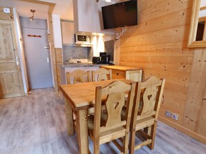 A compact kitchen with a microwave, toaster, and coffee maker. There is a wooden dining table with chairs. - Charming 2-room ski-in, balcony, pets allowed (Méribel)