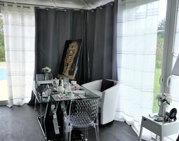 Una habitación moderna con una mesa de comedor de vidrio, sillas transparentes, un sofá blanco y un cuadro de un tigre en la pared.
