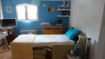 A bedroom with a bed, bedside table, TV, and a window.