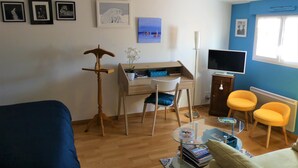 A compact living space with a bed, a desk with a chair, a TV, and two yellow chairs. - Chambre d'hôte Blanche Pierre B&B (Le Perrier)