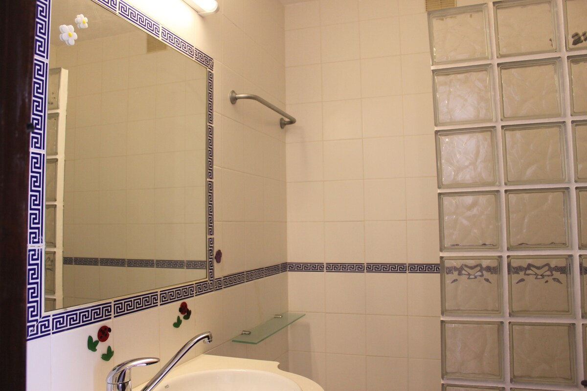 A bathroom with a sink, mirror, and shower area.