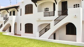 A row of white buildings with multiple balconies and a staircase. - Apartamentos Posidonia (Mercadal)