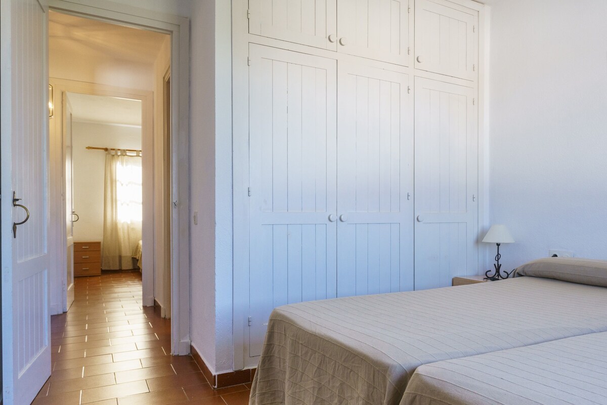 A bedroom with a bed, a wardrobe, and a nightstand with a lamp.