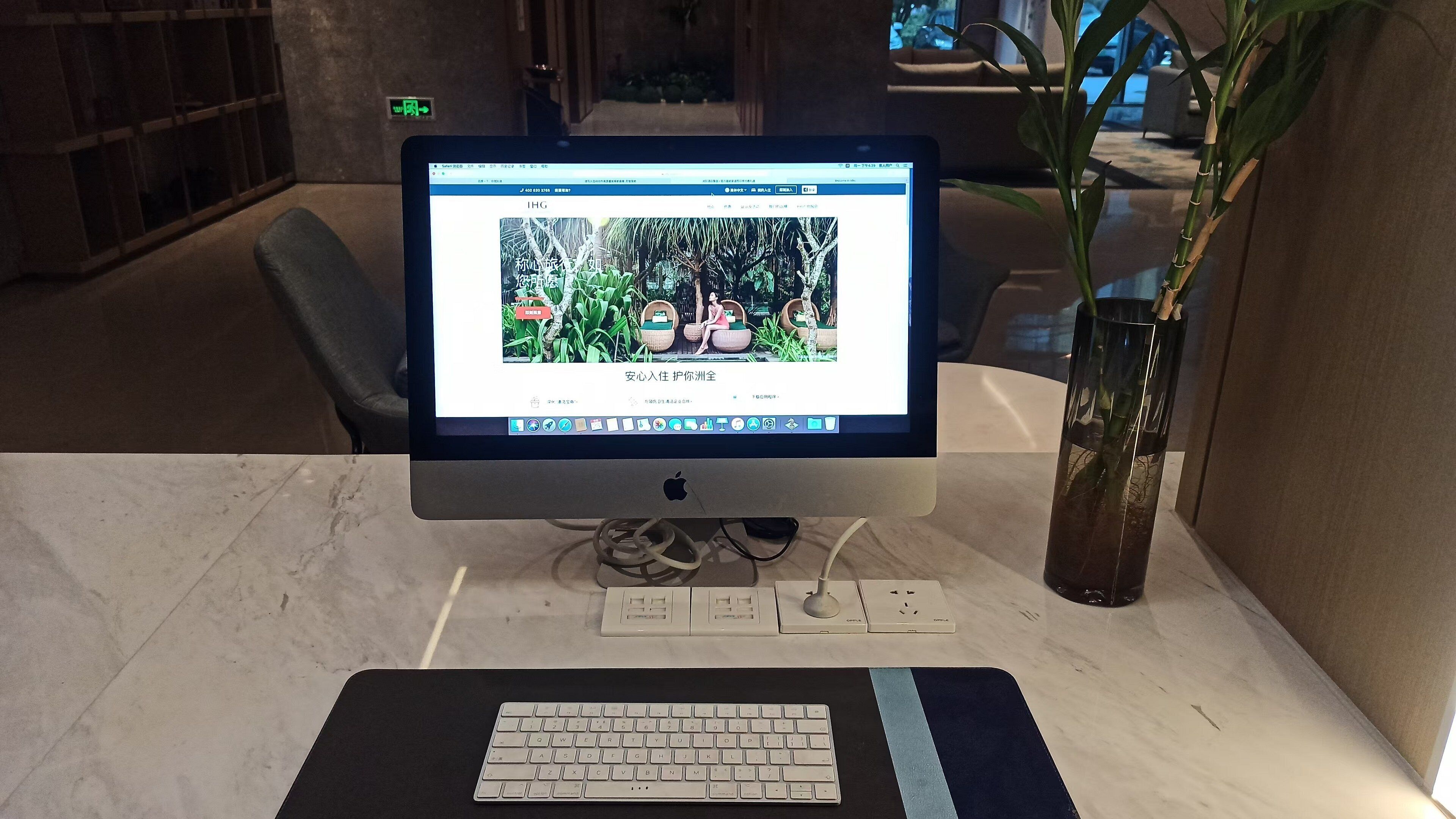 Een bureautocomputer met toetsenbord op een marmeren tafel, een vaas met een plant en een stoel op de achtergrond.