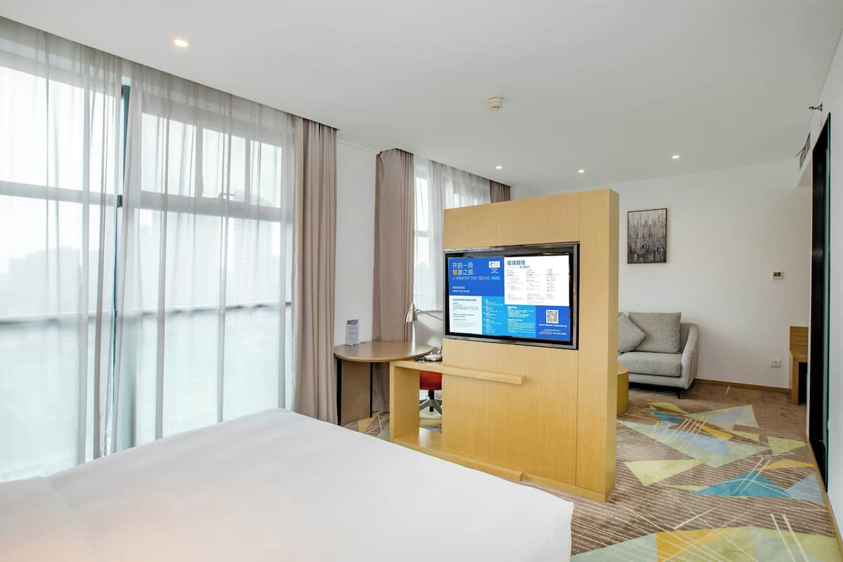 A hotel room with a bed, a desk, a TV, and a sofa.