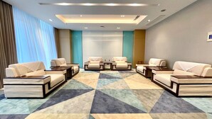 A hotel lobby with a geometric patterned carpet, multiple seating areas with sofas and armchairs, and a large window with curtains. - Holiday Inn Express Changzhou Xinbei by IHG (Changzhou)