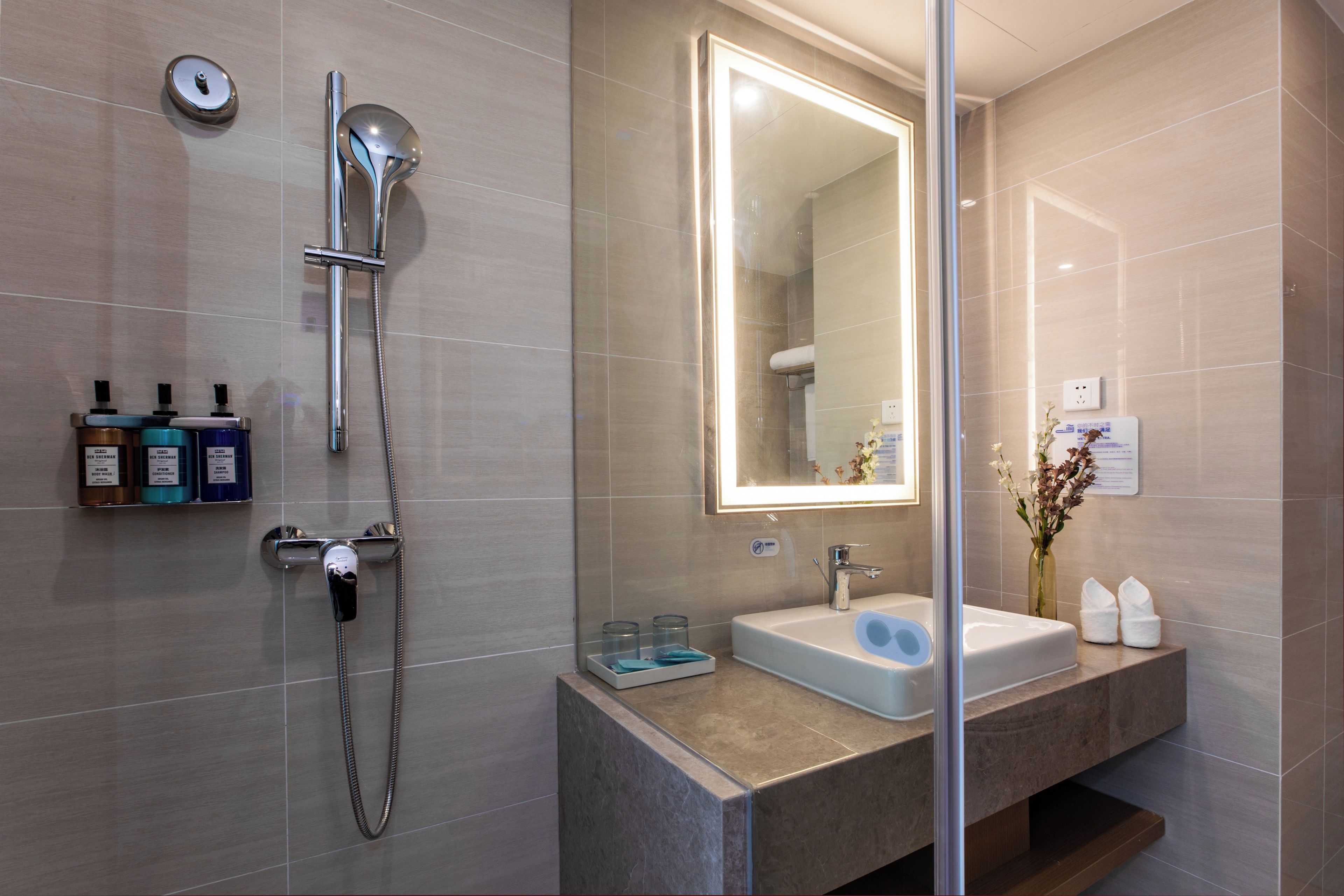 Un baño moderno con ducha, lavabo y espejo.