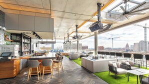 A modern rooftop bar with a bar counter, seating area, and a view of the city skyline. - The Otis Hotel Austin, Autograph Collection (Austin)