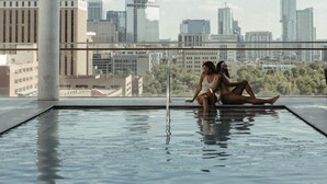 An indoor swimming pool with a cityscape view, large windows, and a modern architectural design. - The Otis Hotel Austin, Autograph Collection (Austin)