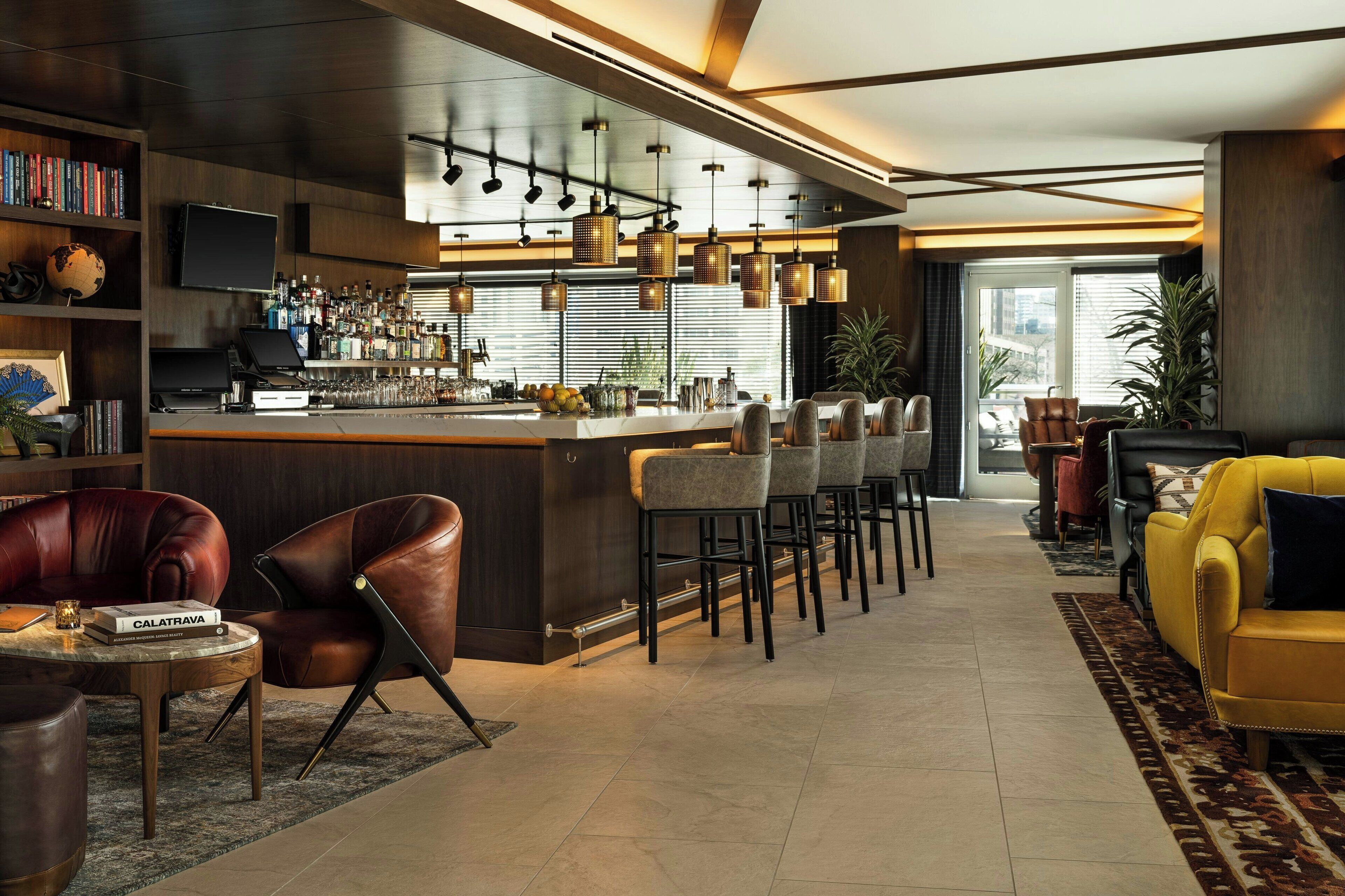 A modern bar area with a long counter, multiple bar stools, and a television mounted on the wall.
