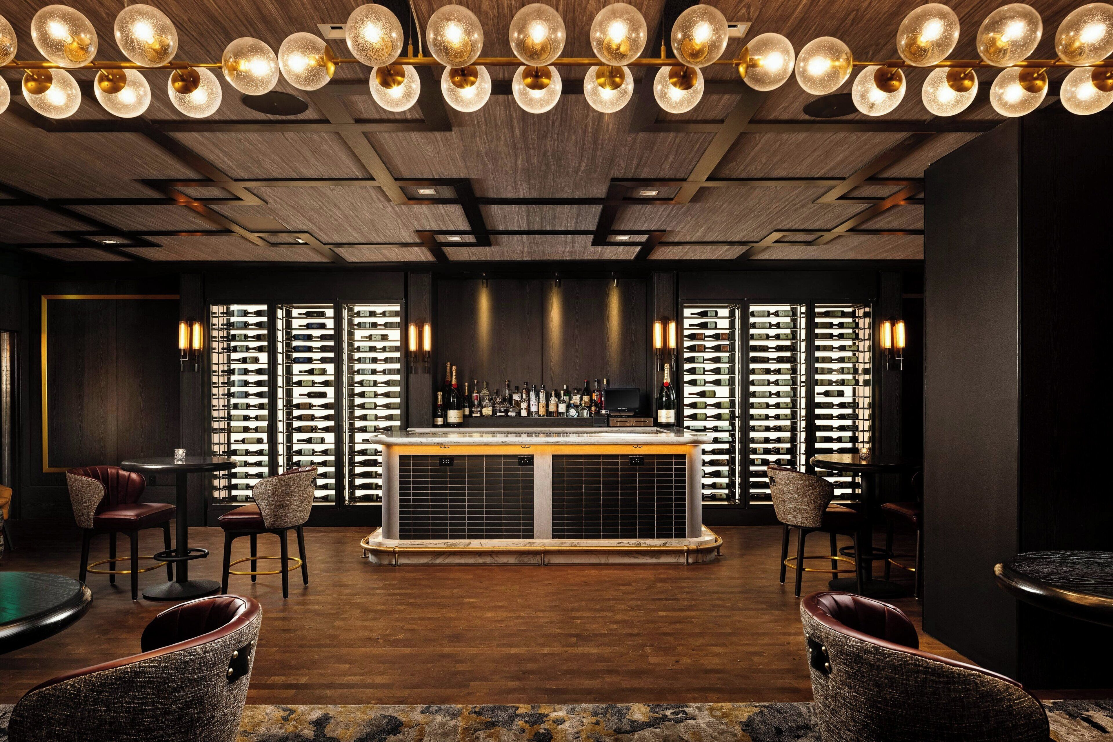 Un espace bar doté d’un plafond en bois, d’un meuble à vin et de sièges.