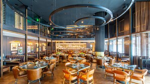 A spacious restaurant with multiple dining areas, high ceilings, and modern lighting fixtures. - The Otis Hotel Austin, Autograph Collection (Austin)