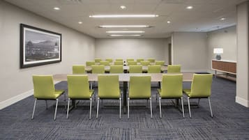 A conference room with a long table and chairs, carpeted floor, and a framed picture on the wall.