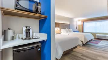A hotel room with a microwave, coffee maker, and a compact dishwasher. The room has two beds with white linens and a large window offering a city view.