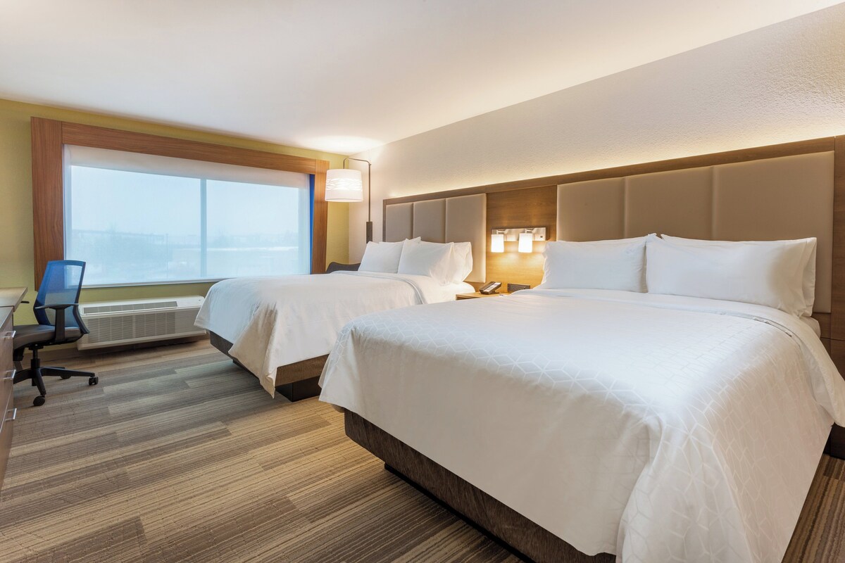 Habitación de hotel con dos camas, un escritorio y una silla.
