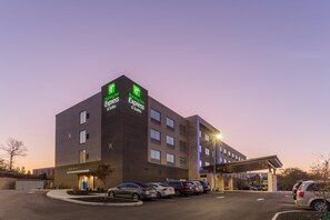 Un hotel Holiday Inn Express con estacionamiento y un corredor cubierto.