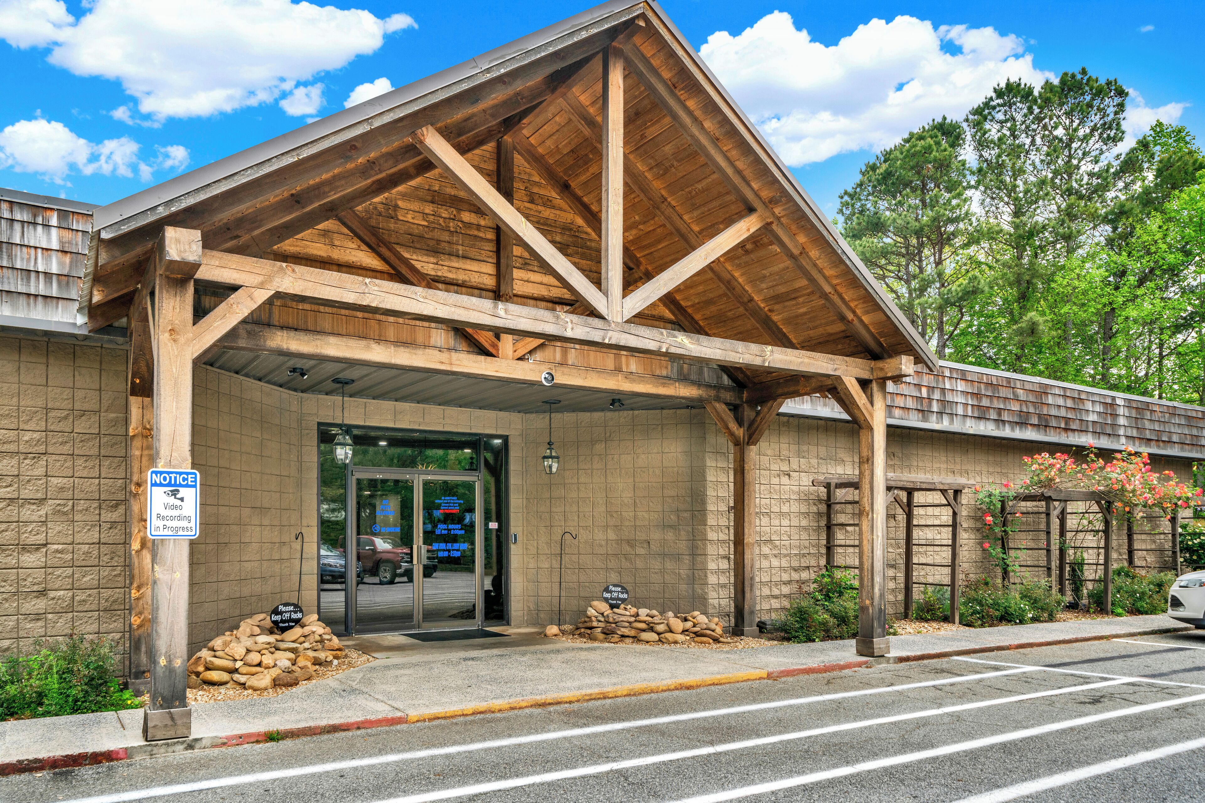 A building with a wooden structure, a sign indicating video recording, and a pile of stones.