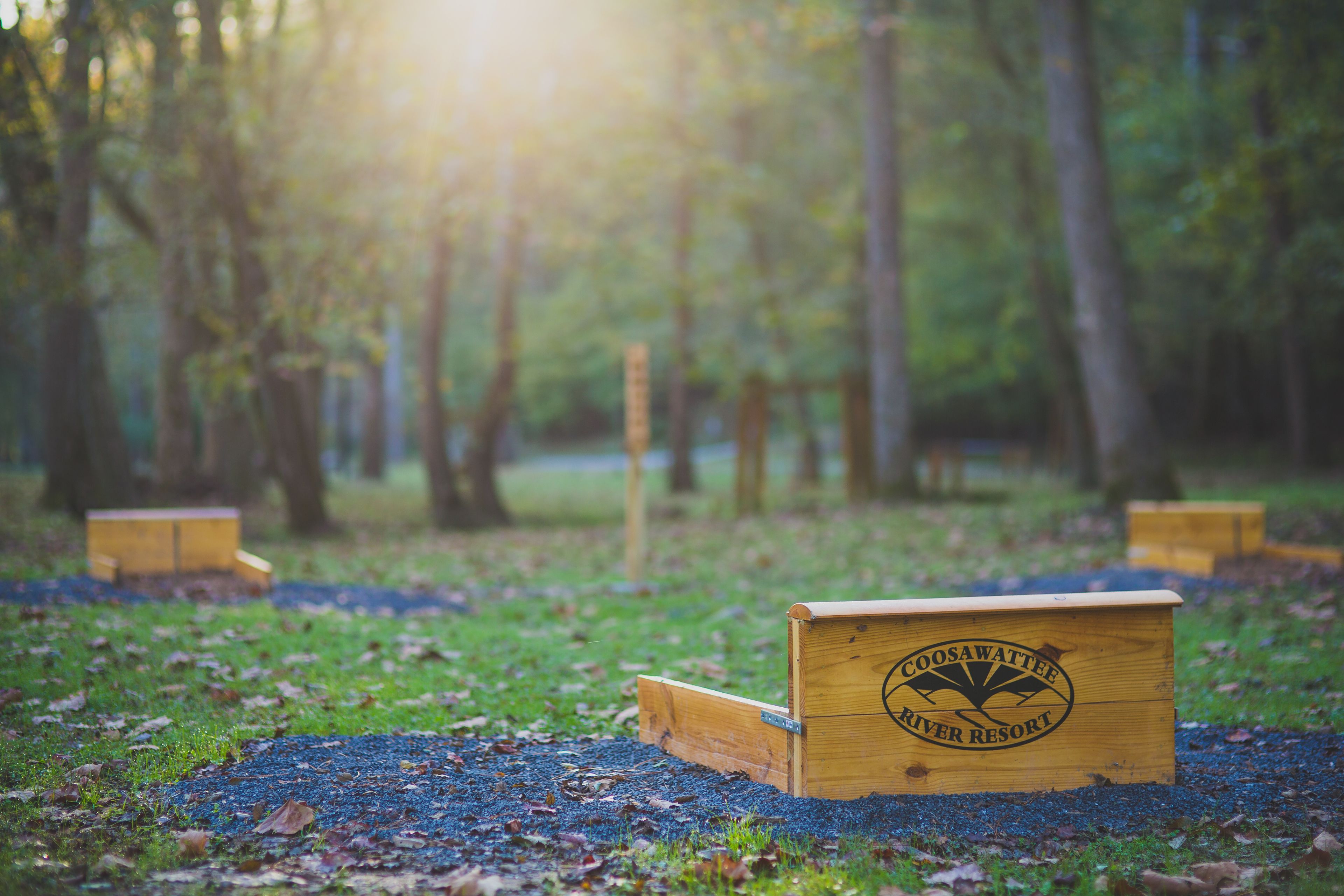 A wooden box with the text "Coosa Waterway River Resort" on a grassy area with trees in the background.