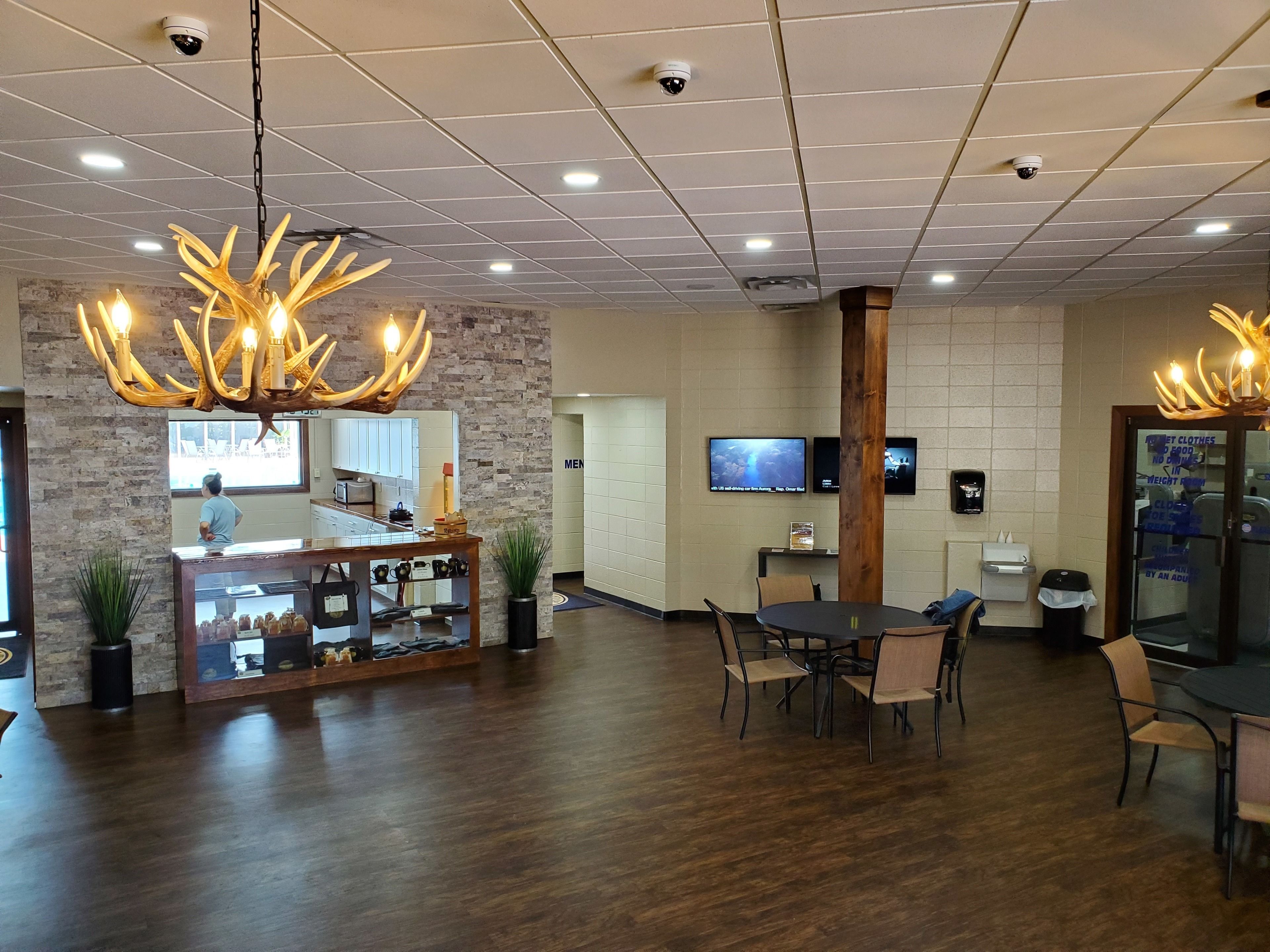 A lobby with a reception desk, a wooden floor, a chandelier, and a television screen.