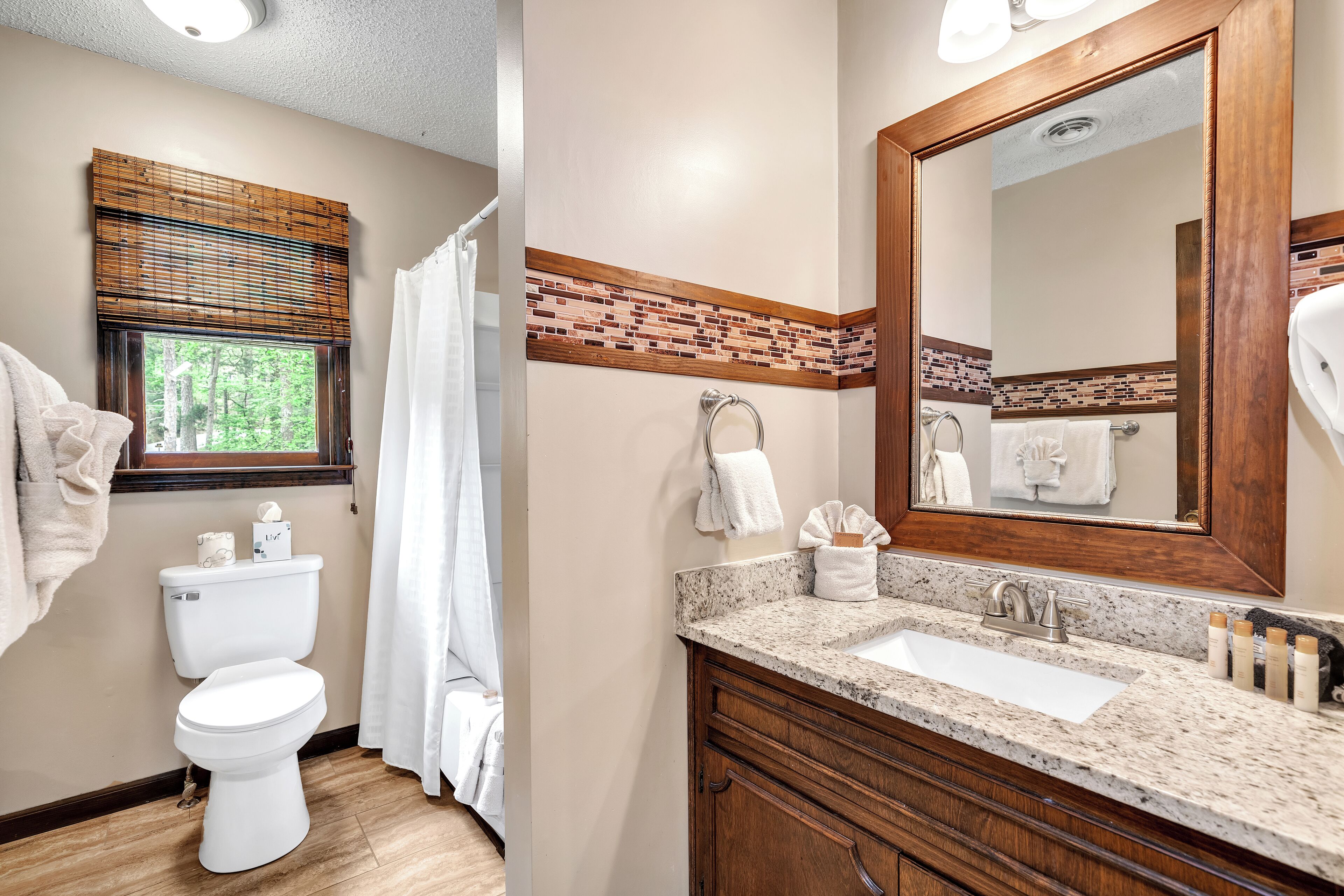 A bathroom with a toilet, sink, and mirror.
